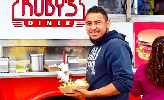 Man standing in front of a Ruby's Diner with food in his hands